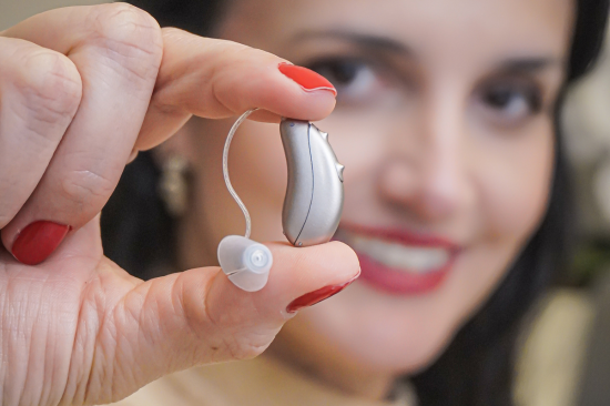 Aparelho auditivo discreto, na mão da doutora.