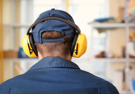 Trabalhador usando protetor auricular em ambiente industrial.