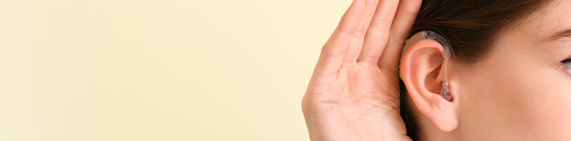 Imagem de uma mulher com a mão no ouvido, tentando ouvir melhor.