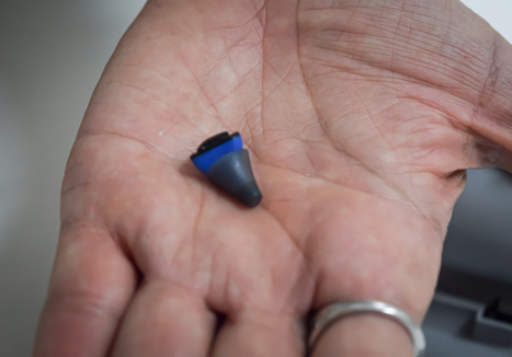 Aparelho auditivo discreto na palma da mão, representando modelo disponível para aluguel de aparelho auditivo na Audiba