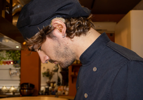 Jovem adulto usando aparelho auditivo discreto, representando o público do aluguel de aparelho auditivo