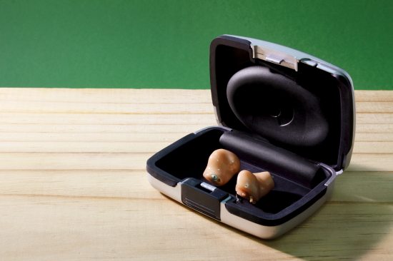 Onde comprar aparelho auditivo - aparelhos auditivos intracanais em estojo aberto sobre mesa de madeira.