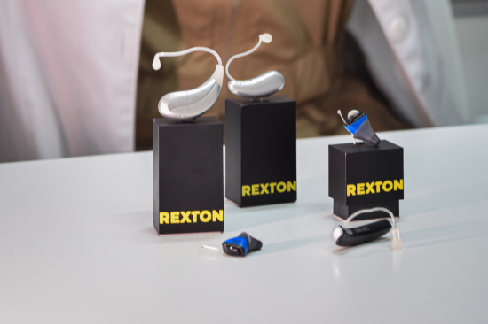 Modelos de aparelho auditivo Rexton expostos sobre a mesa, incluindo versões discretas e potentes.